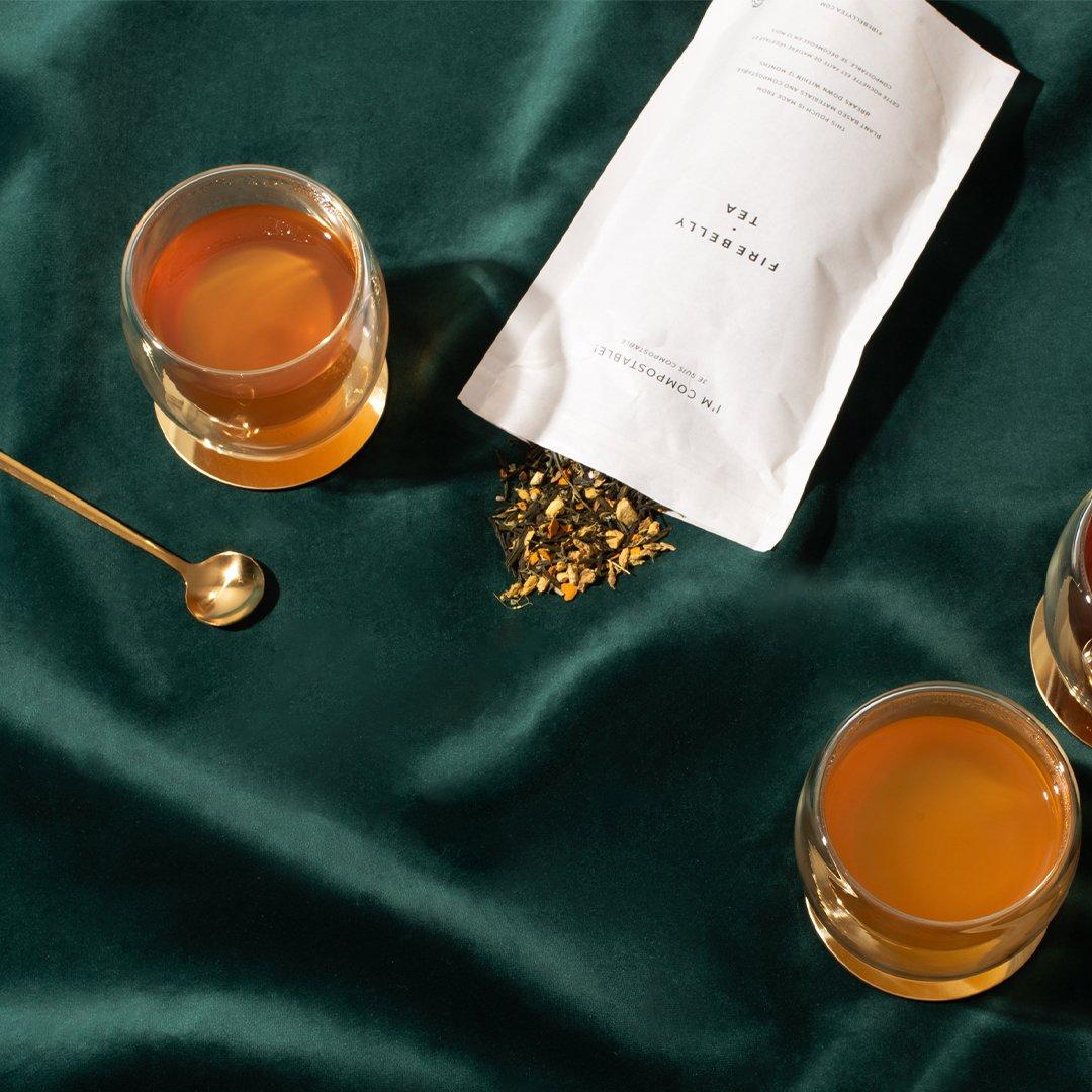 Verres de thé ambré posés sur un tissu vert, ambiance chaleureuse